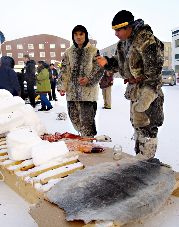 Paul Davidee, right, and Anaga Michael, left, dressed in sealskins, eat frozen char Feb. 6. The pair were demonstrating traditional Inuit skills to visitors in town for the G7 summit.