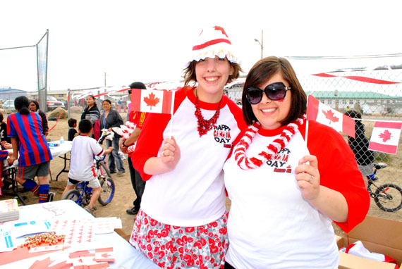 Arianne Gravel and Meaghan Manuel, who are working this summer for the City of Iqaluit, gave out flags and other good Canadian goodies at Canada Day celebrations in Iqaluit July 1. Iqaluit residents marked the day with a traditional parade, followed by lots of music and games from kids in front of Nakasuk School. (PHOTO BY JIM BELL)