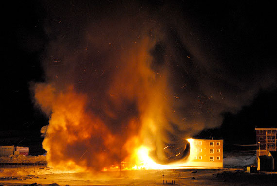 A large plume of super-heated air and gas explodes into the air during a fire that consumed building 4100 in Iqaluit in the early morning hours of March 24. The 29-unit apartment building smouldered for much of the day. About 60 people have been left homeless, but no one was injured. The Iqaluit fire department said the fire began on the outside of the structure but worked its way into the building. Firefighters managed to knock the fire down on the building's exterior, but after flames and smoke quickly engulfed the interior, the entire structure was lost. The fire department is continuing work at the site, which is located near the Lake subdivision. On March 24 and March 25, residents may help the fire's homeless victims by donating clothing, bedding and housewares at Inuksuk High School between 8:00 a.m. and 8:00 p.m. each day. (PHOTO BY AARON WATSON)
