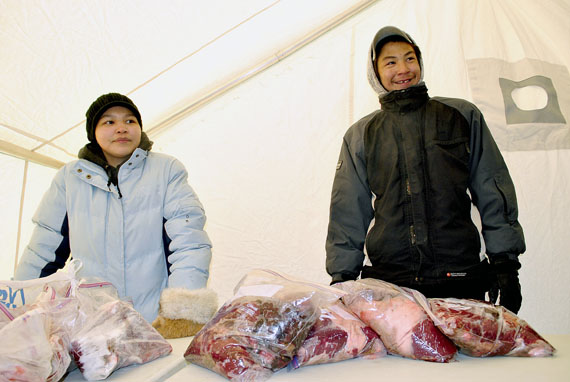 Market forces: Eeta Nuqingaq (left) and a family member sell polar meat at a country food market held March 12 in Iqaluit, at Iqaluit Square, in front of the elders centre. Organizers expect the market to become a monthly event. Anyone able to sell country food legally may sell their produce at these markets and keep all the money they receive. Money from the Department of Economic Development and Transportation helps pay for the event. (PHOTO BY JIM BELL)