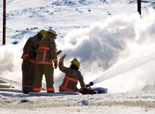 Firefighters exchange a high five after more than eight hours battling a massive blaze that levelled at three-story apartment building in Iqaluit's Road To Nowhere subdivision March 24. (PHOTO BY CHRIS WINDEYER)