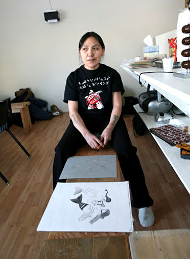 Mary Paningajak Alaku poses front of a drawing that she is in the process of transforming into a print. Paningajak Alaku participated in a 16-day storybook-making workshop in Ivujivik in March, where local women illustrated elders’ stories. (PHOTO BY GILLES BOUTIN)