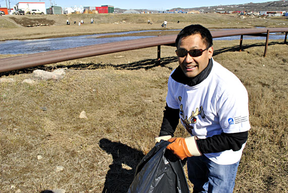 Chad Aramburo, a CanNor employee, picks up trash by the airport road creek in Iqaluit June 17, part of a community-wide cleanup effort in which teams of volunteers have spread out throughout Iqaluit to clean up the mess left behind by this spring's melting snow. (PHOTO BY JIM BELL)