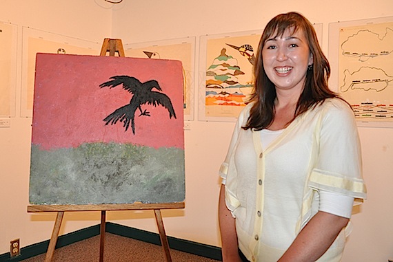 Naya Maurice of Iqaluit poses next to a painting that she entered in the Raven Harmonies Design Competition, a territory-wide art contest launched by the Alianait and Nunavut arts festivals. Maurice's painting was selected June 14 as the official logo for this year's events and the image will appear on festival t-shirts. The acrylic painting, done on an old ceiling tile from Inuksuk high school, was inspired by her dog chasing ravens on the tundra, Maurice said. (PHOTO BY SARAH ROGERS)