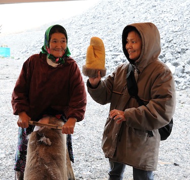 Sarah Pasha Annanack and Charlotte Morgan show cruise ship passengers how to make a mitten from a caribou hide Sept. 21 during the Clipper Adventurer's Sept. 21 stop in Kangiqsualujjuaq. (PHOTO BY PASCAL POULIN)