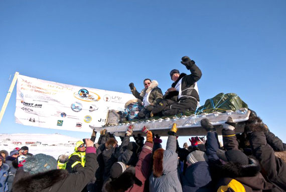 Kangiqsujuaq mushers Peter Kiatainaq and son Peter Kiatainaq Jr. are hoisted high after crossing the 2012 Ivakkak finish line in Kangirsuk March 20 at 4: 30 p.m. This marks the sixth victory for the Kangiqsujuaq musher and his dog team. The rest of the race's 11 teams were still arriving in Kangirsuk March 21. Watch www.nunatsiaqonline.ca for more race coverage. (PHOTO BY PIERRE DUNNIGAN/COURTESY OF MAKIVIK CORP.)