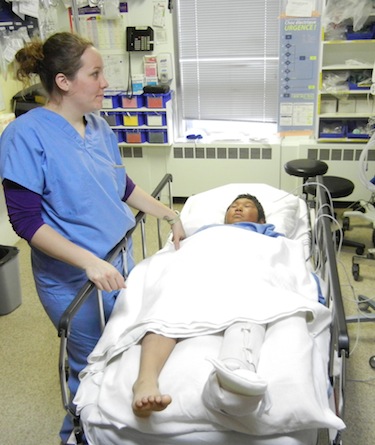 Nurse Marie-Pierre Larose stands by Adamie Ohaituk, 10, of Inukjuak, who's waiting for a doctor to put a cast on his broken leg. (PHOTO BY JANE GEORGE)
