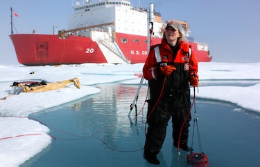 Scientist Karen Frey takes optical measurements in a melt pond, with the U.S. Coast Guard Cutter Healy on the background. (NASA HANDOUT PHOTO)