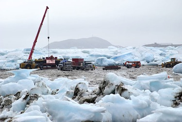 A shipping company's costly nightmare: heavy sea ice clogs the waters of Frobisher Bay this past August, forcing workers to use heavy equipment to clear a path through the ice to this barge bringing in goods. (FILE PHOTO)