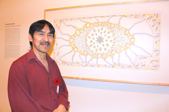 Renowned Cape Dorset printmaker and graphic artist Qavavau Manumie poses next to 