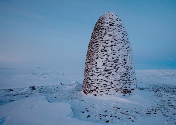 A stone cairn built by Norwegians eager to see the Maud, the ship once sailed by their polar hero Roald Amundsen, back in Norway, now stands on the shore outside the town of Cambridge Bay. In the distance you can see the Maud, frozen where it sank at its mooring in 1930. Read more about why the manager of the 