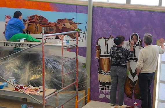 Mural artist Ele Davis from Calgary, centre, works with local artists on a mural in Cambridge Bay's May Hakongak Library and Cultural Centre which commemorates the 100th anniversary of the Canadian Arctic Expedition. (PHOTO COURTESY OF THE KITIKMEOT HERITAGE SOCIETY)