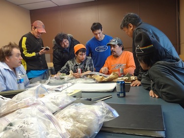 Michael Beauregard, resident geologist with the Government of Nunavut’s department of economic development and transportation talks with carvers Jermaine Napayok, Thomas Angoo, Abraham Eetak, Bill Jar, carving instructor Jerry Ell, Salomonie Pootoogook and Noah Enowyak during NACA'S recent carving symposium in Arviat. Here, they are looking at different stones and pictures of different stone quarries. (PHOTO COURTESY OF NACA)