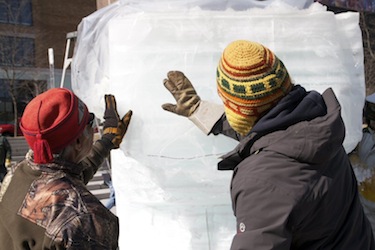 Carvers examine their ice bear carving now on display in downtown Montreal. (HANDOUT PHOTO)