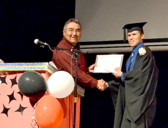 Makivik Corp. president Jobie Tukkiapik hands an Air Inuit bursary to 2013 Jaanimmarik School graduate Michael Petagumskum, who also received a Diamond Jubilee medal for his involvement in Kuujjuaq's Junior Canadian Rangers patrol where he is an assistant patrol leader. Graduates Kyle Aitchison and Justin Lingard also received Air Inuit bursaries. See more photos later from the June 13 convocation ceremony at Kuujjuaq's Katittavik town hall auditorium on the Facebook page of Nunatsiaq News. (PHOTO BY ISABELLE DUBOIS)