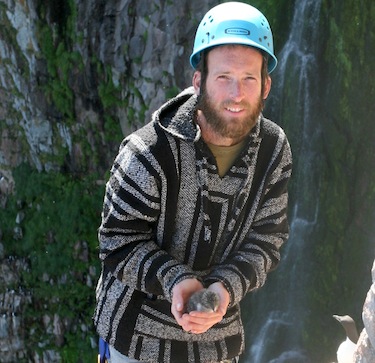 Kyle Elliott holds a murre chick on Coats Island where he and other researchers have found many dead chicks, decapitated by polar bears. (PHOTO BY KENNY WOO)