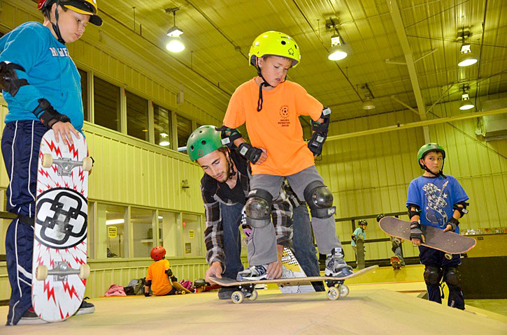 Instructor Roger Besserve, 26, helps a youngster preparing to roll down a ramp at the Iqaluit skate park Aug. 28 as part of the summer skate camp put on by the City of Iqaluit. The camp drew 30 kids this year — the biggest turnout ever. (PHOTO BY DAVID MURPHY)