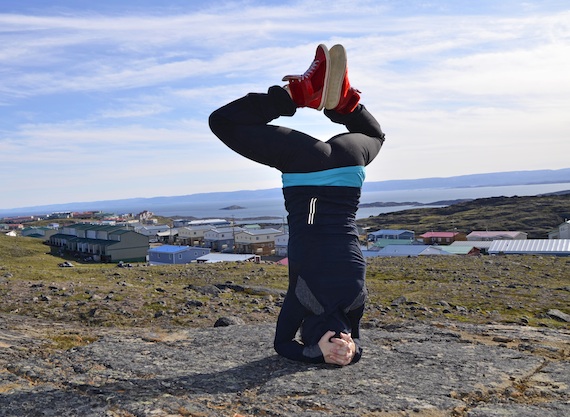 Christine Lamothe, a former break dancer who teaches yoga and hip hop dancing in Iqaluit, stands on her head and stretches her legs in a yoga pose while overlooking Iqaluit. Read more about Lamothe's plans to set up a yoga 