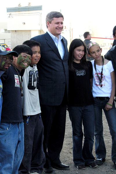 Prime Minister Stephen Harper poses with children behind Nakasuk School in Iqaluit during his first visit to the Arctic in August 2006. Many of the messages contained in his government's Oct. 16 throne speech date back to his early Arctic tours. (FILE PHOTO)
