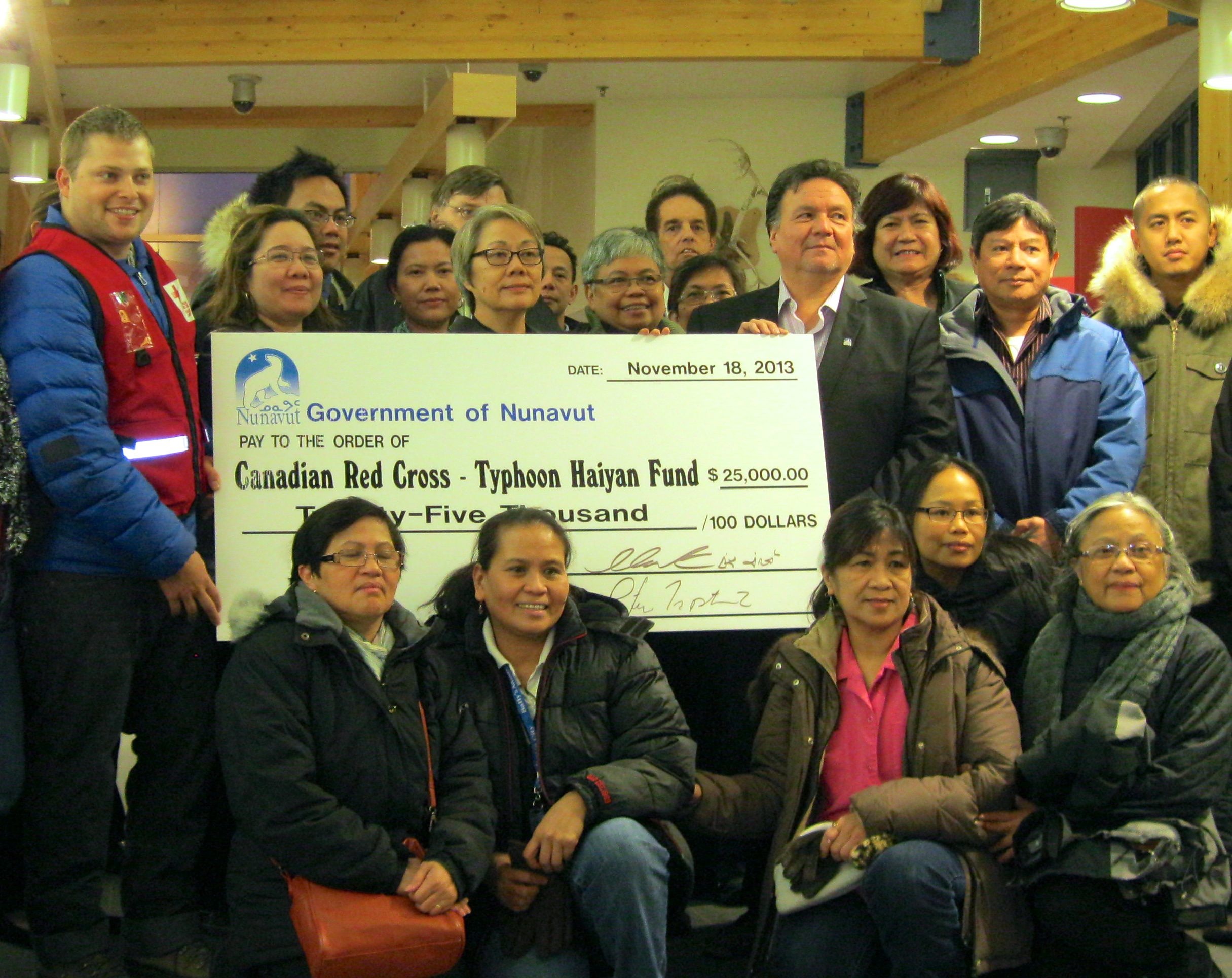 Nunavut's outgoing Premier Eva Aariak, centre, behind cheque, and incoming Premier Peter Taptuna, right, announced a territorial government contribution of $25,000 in relief for victims of Typhoon Haiyan  in the Philippines, Nov. 18, at a gathering with members of Iqaluit's Filipino community in the Legislative Assembly. The funds go to the Canadian Red Cross, for food, water and sanitation aid in disaster-stricken areas of the country, said Michel Rhéault of the Red Cross, far left. 