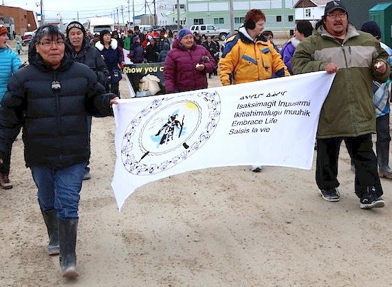 Two marchers carry an Embrace Life banner and small candles during a World Suicide Prevention Day walk in Cambridge Bay last September. Inuit Tapirrit Kanatami is now working to develop an Inuit-specific suicide prevention strategy. (PHOTO BY RED SUN PRODUCTIONS)