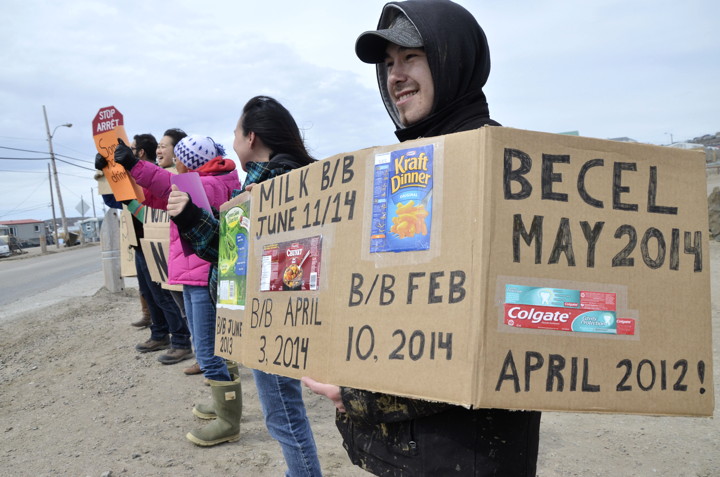 Norman Nungaq holds up a cardboard sign June 14 that displays recently purchased products that had already expired. (PHOTO BY DAVID MURPHY)   
