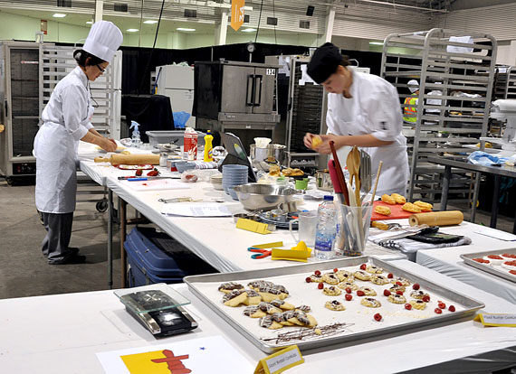 Terri Angalik, left, a member of Arviat's Skills Nunavut baking club, works to prepare a pie crust at the International Centre in Mississauga, Ont. June 5. Some of Angalik's finished products are on display for judging: short bread and piped butter cookies. (PHOTO BY SARAH ROGERS)