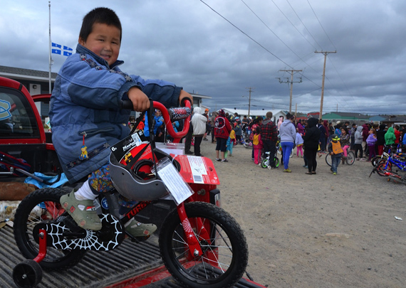 Three-year-old Jackie Sequaluk shows off the brand new bicycle, helmet and lock he won at the Kuujjuaq bike rally July 23. The annual event, coordinated by the Kativik Regional Police Force's Cadet program.  is held to promote bike safety. (PHOTO  BY ISABELLE DUBOIS) 