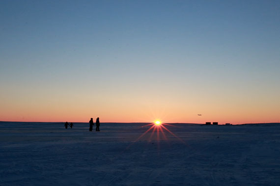 As the sun sets at 2:22 p.m. Nov. 9 over Cambridge Bay, four children play on the ice while a Canadian North aircraft comes in to land. (PHOTO BY RED SUN PRODUCTIONS)