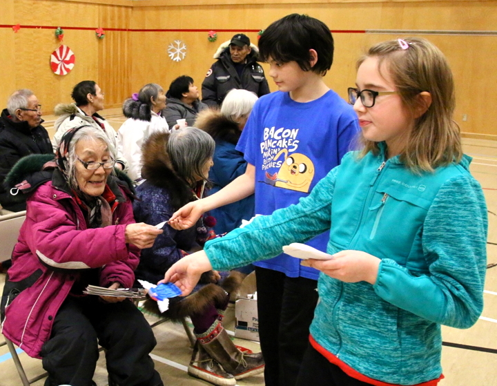 Students at Kullik Ilihakvik elementary school in Cambridge Bay put on a special Inuinnaqtun Christmas performance for elders Dec. 16. Grade 6 students Sebastian Qaumariaq, middle, and Tara Corey, hand out homemade angels with 