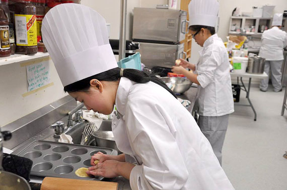 Taking the heat in the kitchen: Kyla Kent, a 15-year old grade 10 student, bends over a moulding pan at Inuksuk High School's kitchen April 28. Kent, along with over 50 other students from across Nunavut, is competing in the Territorial Skills Competition. Kent is vying for the top performance in the baking category at the tenth annual competition--one of fifteen disciplines students are competing in April 28. (PHOTO BY THOMAS ROHNER)