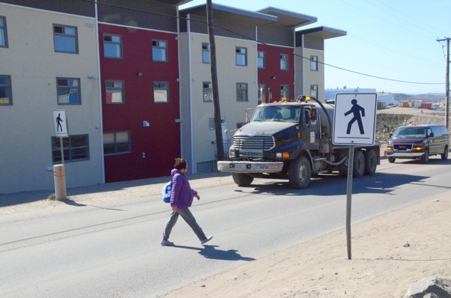 A woman crosses the road between the Tammaativvik Boarding Home and the Qikiqtani General Hospital in Iqaluit July 23. Coun. Noah Papatsie called this crossing “dangerous.” City Council is hoping the GN can pay for beefed up safety measures there. (PHOTO BY DAVID MURPHY) 