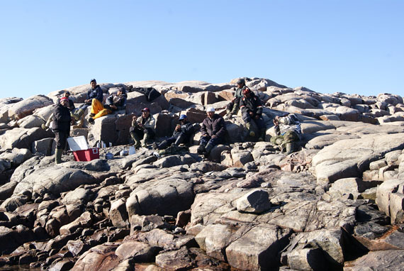 Tired Naujaat hunters gather by the rocky shoreline to rest after the all-night effort required to land their bowhead whale. (PHOTO BY MAY LAIN)