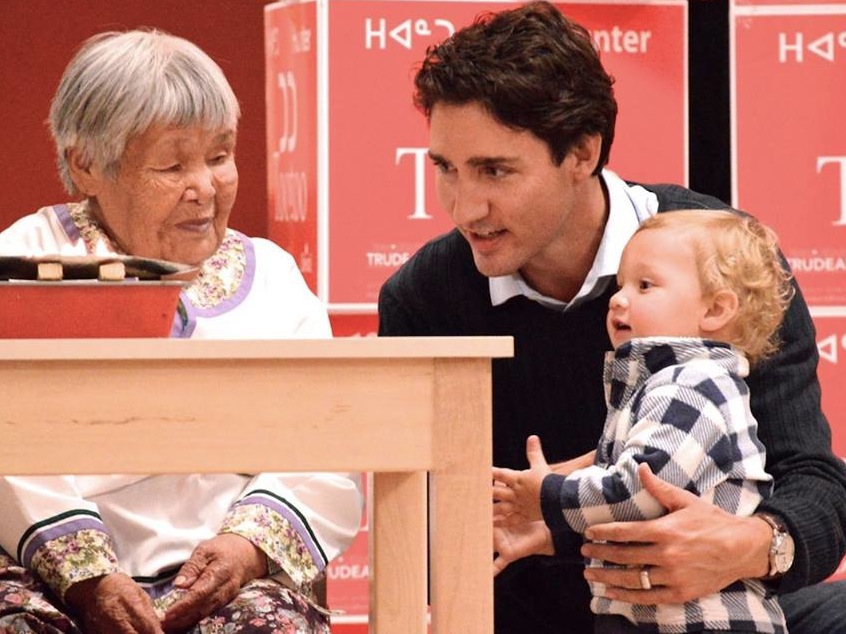 Inuapik Sageaktook, Liberal leader Justin Trudeau, and his 18-month-old son, Hadrien, by the qulliq, Oct. 10, at the community feast in Iqaluit. (PHOTO BY STEVE DUCHARME)