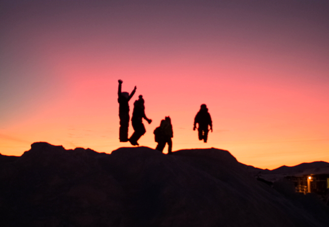 Children jump and play on mounds of snow in Clyde River midday Jan. 18. The pink glow in the sky means the sun should rise any day now; photographer Aimo Paniloo said residents of the Baffin Island community are anxious to see some light after the last several weeks of darkness. (PHOTO BY AIMO PANILOO)