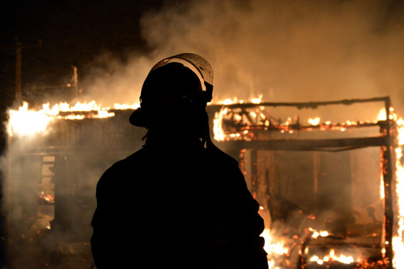 A volunteer firefighter stands before a fire that engulfed a house in the small Nunavik village of Tasiujaq, population about 300, located west of Kuujjuaq on Ungava Bay, after about 7 p.m. April 26. 