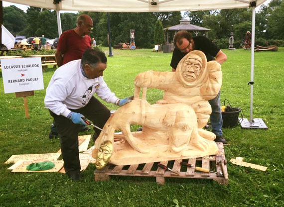 Inukjuak artist Lucassie Echalook, left, puts the final touches on a giant wooden sculpture he created with Quebec artist Bernard Paquet — a larger version of a soap stone piece Echalook created. The artists produced the piece as part of the Anirniq Biennale de Sculpture 2016 in Saint-Jean-Port-Joli, Quebec, an art installment that paired seven Nunavimmiut artists with local artists. The Biennale wrapped up July 24. (PHOTO BY BEATRICE DEER)