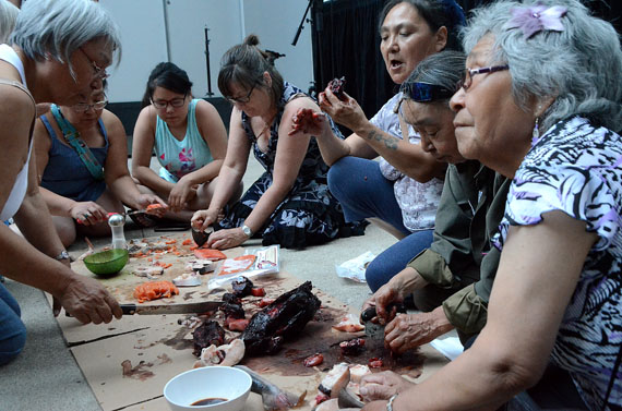 Women cut up seal and Arctic char at the FOFA Gallery Courtyard Aug. 4 in Montreal, as part of the Tillutarniit summer screening series. (PHOTO BY DAVID MURPHY) 