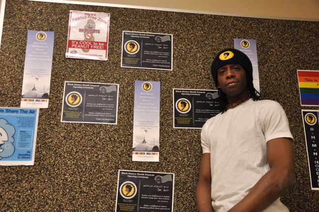Lekan Thomas stands in front of a billboard at Inuksuk High School in Iqaluit displaying posters with the logo for Black History Month Nunavut that he designed Feb. 7. Thomas, a part-time substitute teacher and janitor at the school who has called Iqaluit home for eight years, is helping to organize a number of events for Black History Month in Nunavut's capital. That includes DJing at the popular Jabula event for the third year in a row, held this year on Feb. 25 at the Legion in Iqaluit. Jabula, in the Ndebele dialect, means 