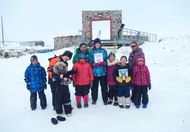 Amy Bruneski, a grade 7 student at Kugaardjuq school, wants to help replace the many books that were lost in the Feb. 28 fire that destroyed the Kugaaruk school. So she wrote to Canadian children’s author Robert Munsch for help. He sent her copies of two of his books, Moose and So Much Snow, which Bruneski (in blue) and her fellow students are holding up in this photo, in front of the entrance of the burnt school. Bruneski, 13, is making a scrap book of photos from the community to send back to Munsch in thanks, and she plans ask him to send more books to start a new library in the community of 900, “so that everyone can read and learn,” she said. Kugaardjuq students are completing the school year in makeshift classrooms around the community, with plans to move into new portable classrooms at the start of the 2017-18 school year. (PHOTO COURTESY OF C. RUTTER)