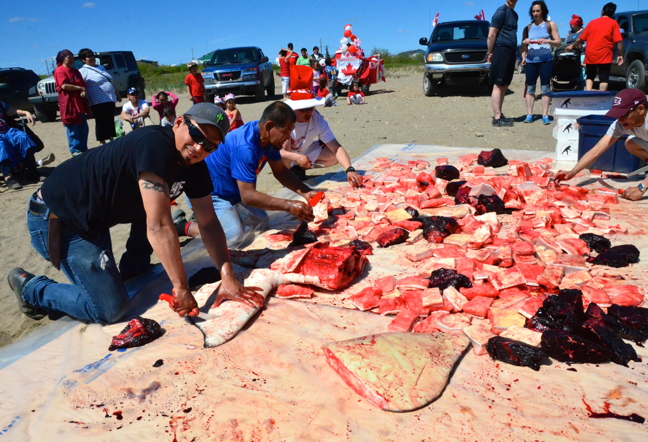 While Ottawans might have celebrated Canada Day with hamburgers and Beavertails, northerners did it northern style: with maktaaq. Hunter George Kauki, left, carves up maktaaq in Kuujjuaq from a beluga he harvested near Kangiqsujuaq with friend Saanti Jaaka. Kauki decided to share the catch with Kuujjuamiut as they gathered on the beach for Canada Day celebrations, to keep alive the Inuit tradition of sharing traditional foods with neighbours. (PHOTO BY ISABELLE DUBOIS)