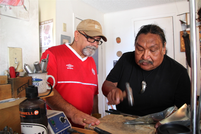 Artist Mathew Nuqingaq, right, shows Shawn Walsh how to hammer out metal during an Aug. 15 qulliq-making workshop in Iqaluit. The workshop was part of the Government of Nunavut's 