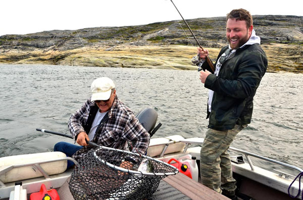 Johnny Reid, right, reels a big salmon into a net while out fishing near Kuujjuaq Aug. 18. Senator Charlie Watt, left, took the popular country crooner and some of his band mates out fishing on the Kuujjuaq River the day after they played a show at the Kuujjuaq Forum as part of Aqpik Jam. This was Reid's second time performing at the annual music festival. (PHOTO BY ISABELLE DUBOIS) 