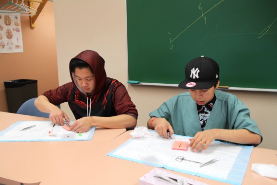 Eeyeevadlok Josephie, left, and Luke Nuliayuk try their hand at surgical suturing. (PHOTO BY BETH BROWN)