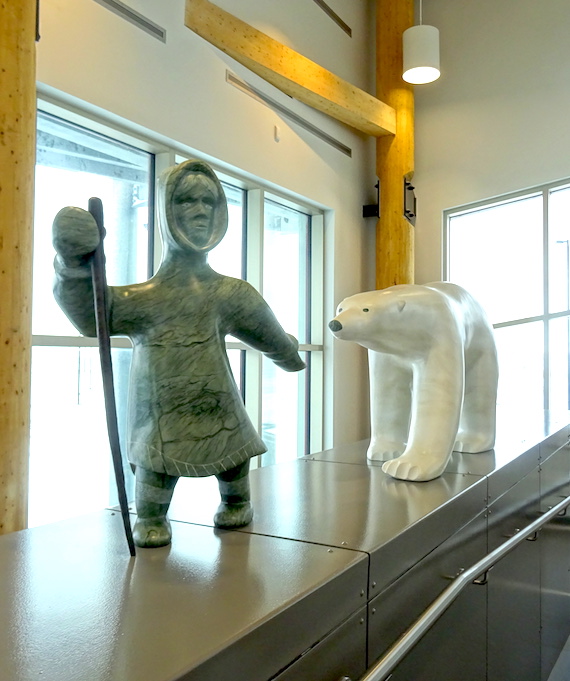 This piece by Koomuatuk (Kuzy) Curley of Cape Dorset is named Ningiuq amma Nanuq (Elder and Polar Bear). It portrays the story of a grandmother who adopted a bear cub, which then grew up. 
