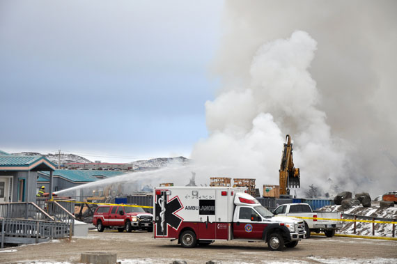 Firefighters continue to water a fire at Northmart's warehouse in Iqaluit, which by mid-afternoon Thursday had been largely destroyed. The company who owns the store says it will distribute its incoming stock among its four convenience stores in the community as well as Iqaluit's other major grocer, Arctic Ventures. (PHOTO BY SARAH ROGERS) 