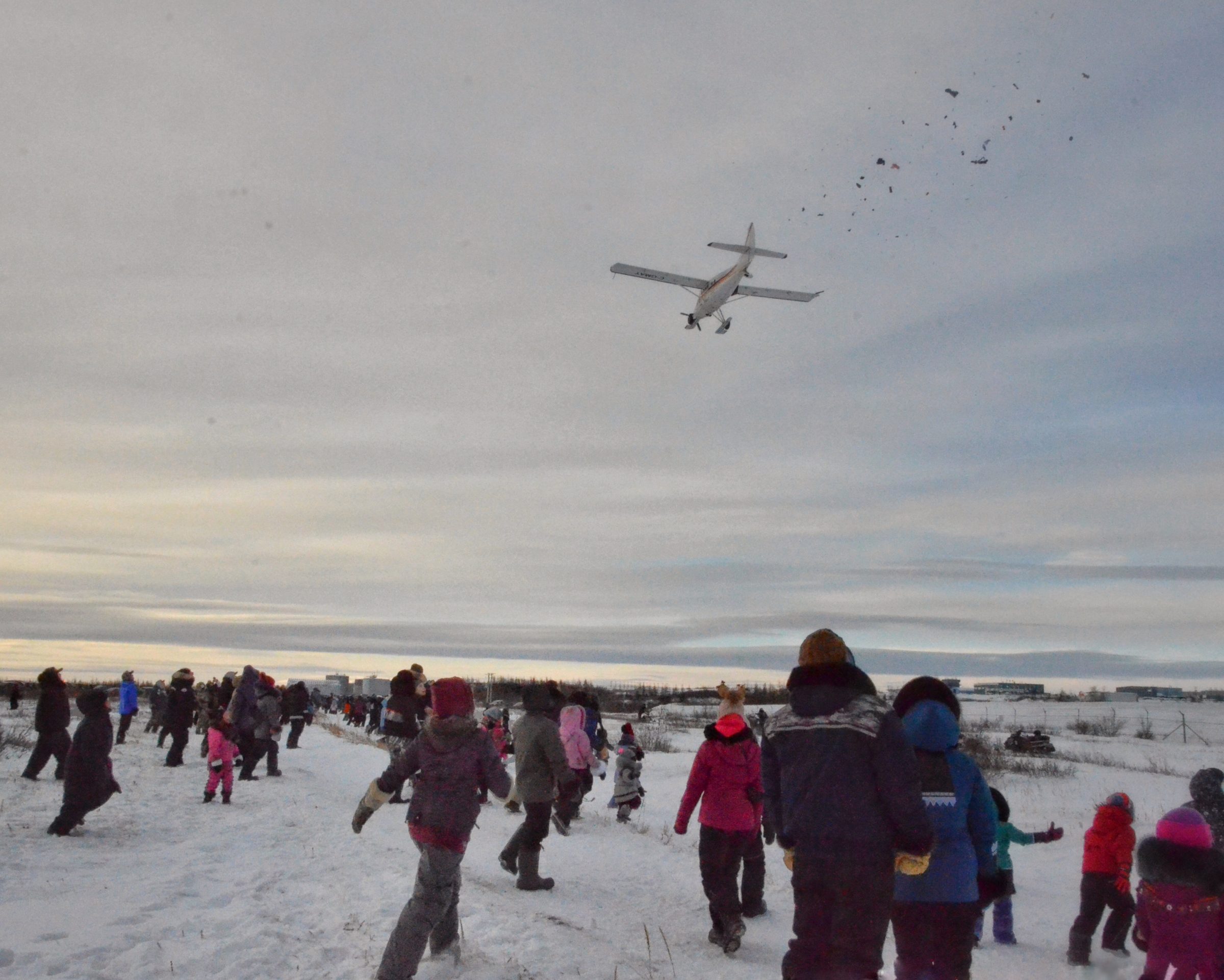 Children run forward eagerly to scoop up the candy and other goodies that fall from the sky over Kuujjuaq at the annual candy drop. The event usually takes place on Christmas Day, but was postponed by one day this year due to strong winds. (PHOTO BY ISABELLE DUBOIS)