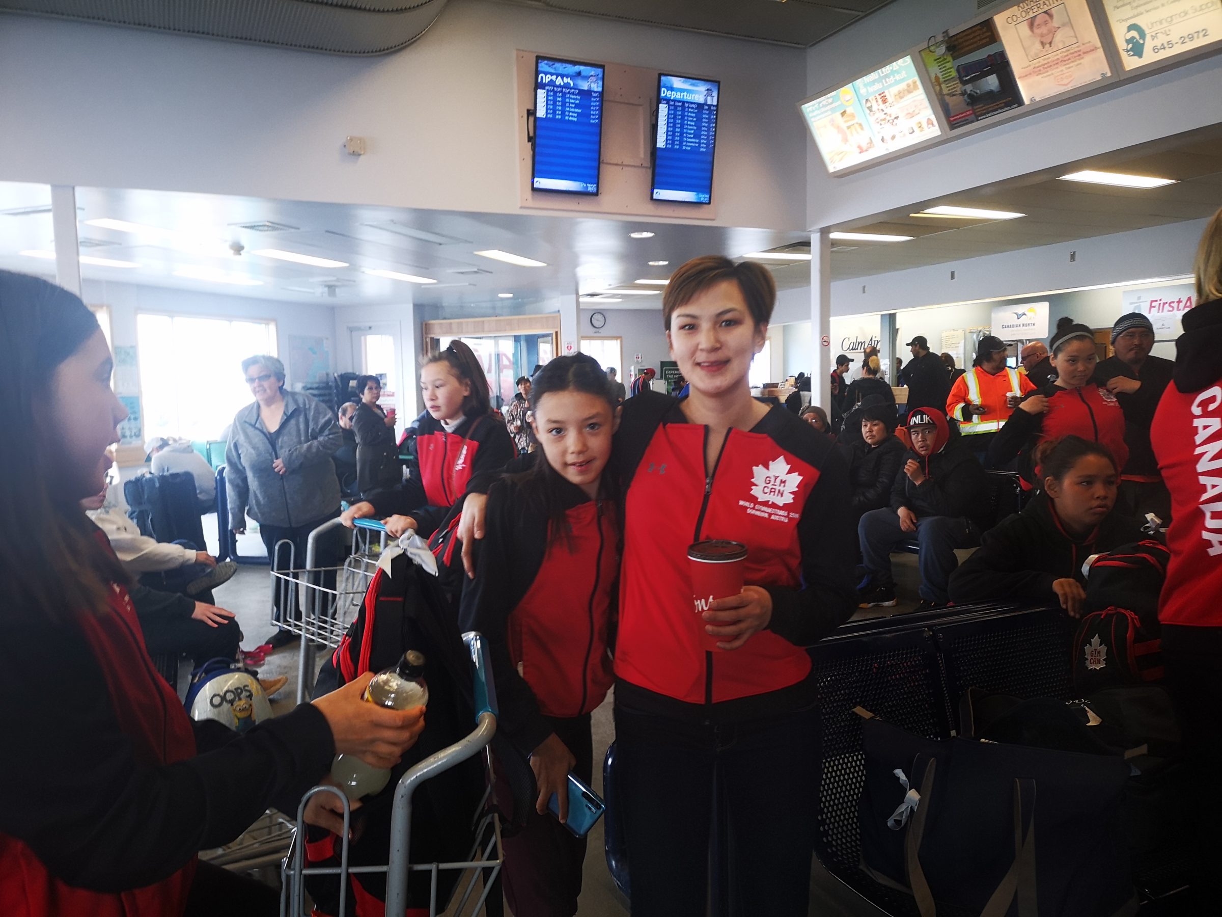 The Aqsarniit Ujauttaq (Northern Lights Gymnastics Club), featuring Tessa Angootealuk and Miuqtugia Angootealuk in the centre of the image, wait for their flight out of Rankin Inlet on Monday, July 1, to Austria to participate in a gymnastics competition. (Photo by Noel Kaludjak)