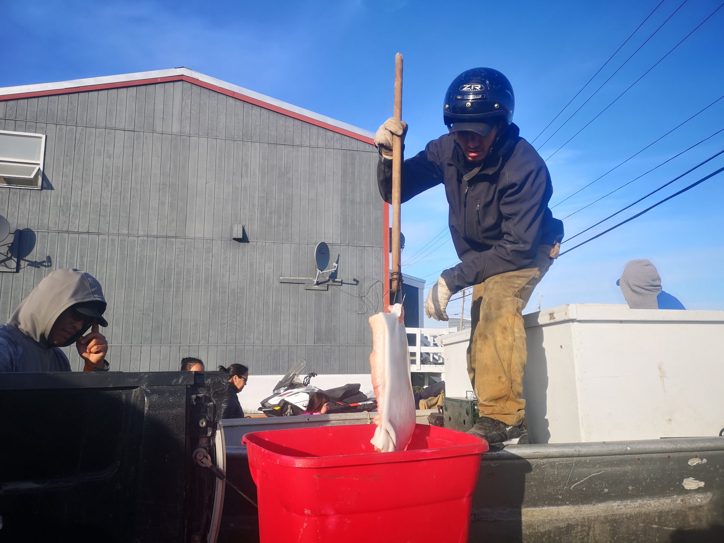 Tuluganak Kaludjak shares some of his muktaaq with Issaluk Tattuinie in Rankin Inlet, following a beluga hunt near the community on Wednesday, Aug. 21. About 25 boats had a successful hunt, and the muktaaq will be shared among residents of Rankin Inlet and nearby communities. (Photo by Noel Kaludjak)