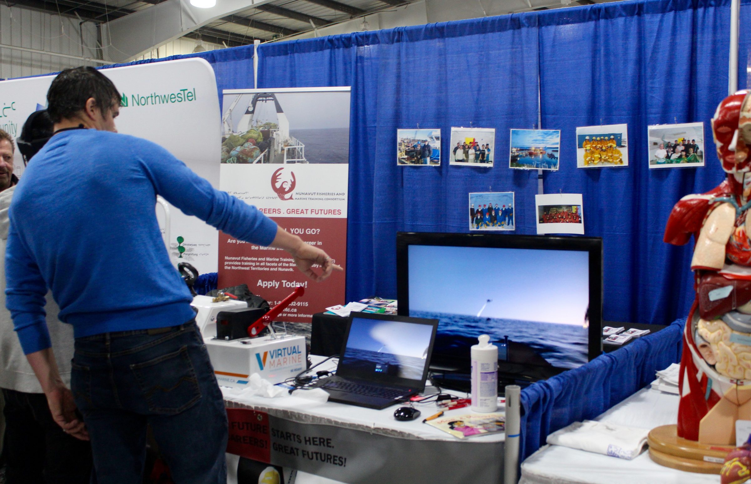 Visitors to the Nunavut Trade Show in Iqaluit check out the Nunavut Fisheries and Marine Training Consortium booth Sept. 19. The trade show ran from Sept. 17 to 19 and featured conference sessions, keynote speakers and over 80 exhibitors. (Photo by Emma Tranter)